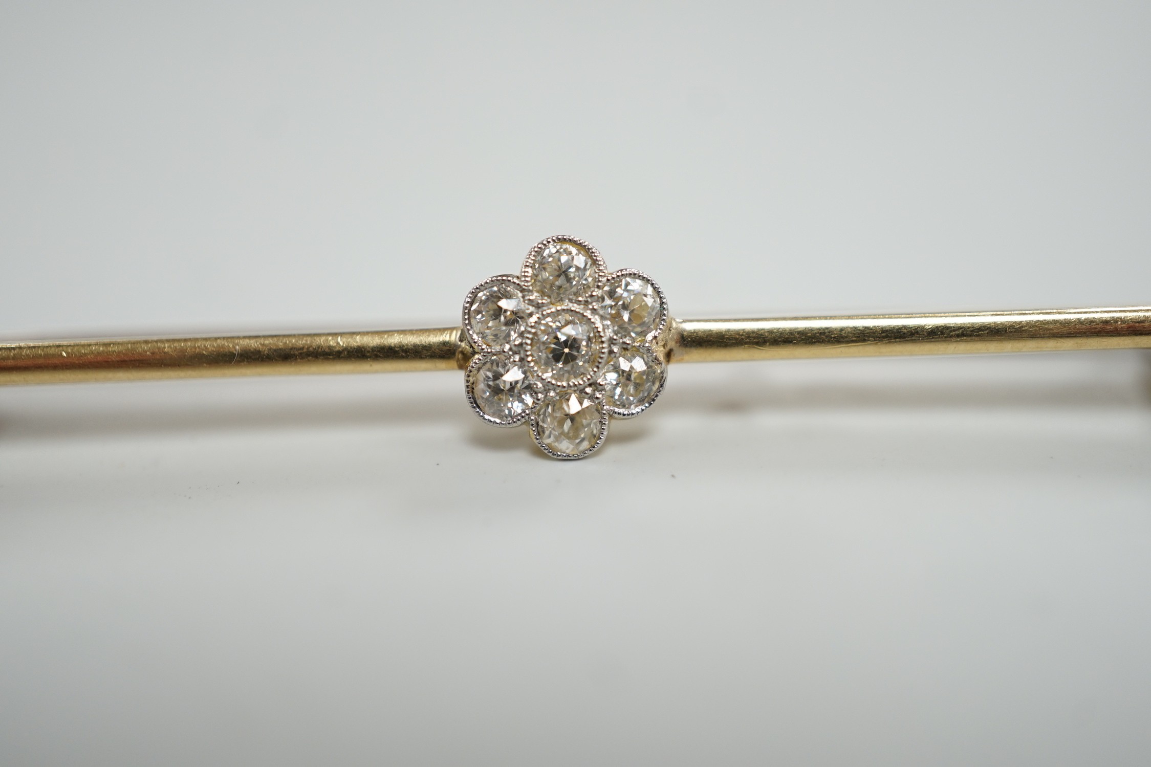 An 18ct and seven stone diamond set flower head cluster bar brooch, 57mm, gross weight 4.7 grams.